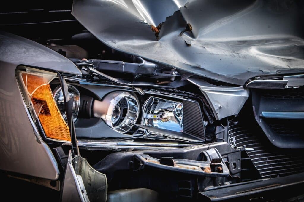 Damaged vehicle being assessed and repaired inside a modern workshop.